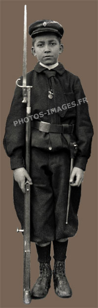 Enfant soldat au garde-à-vous arme au pied dans son uniforme taillé sur mesure
