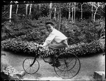 Jeune garçon photographié sur son tricycle dans le jardin de la maison